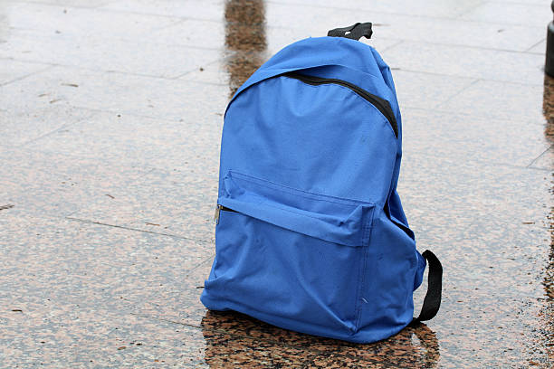istock Blue backpack abandoned on wet street pavement in rain 2252866482