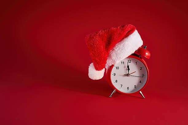 istock Festive Time. A red clock adorned with a Santa hat against a vibrant red background. 2252868414
