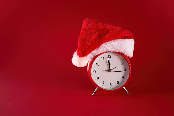 istock Festive Time. A red clock adorned with a Santa hat against a vibrant red background. 2252868415