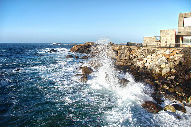 Two senior mixed race friends explore their home city while on vacation. They are walking along the Seapoint Promenade enjoying the views over the sea as the waves splash