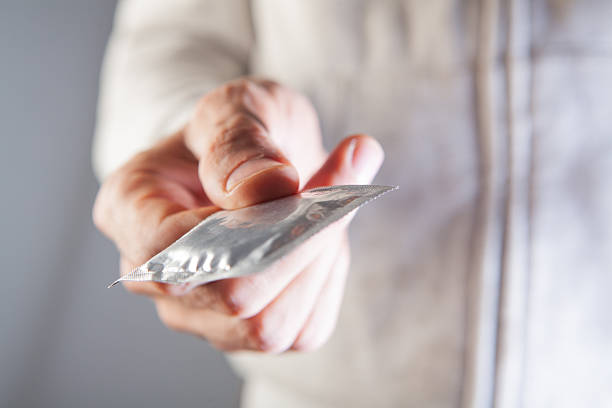 man in a white shirt holding a condom in her hands.