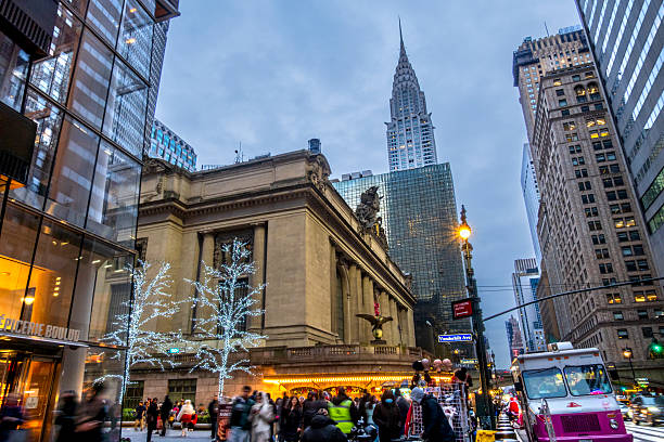 New York, NY - US - Dec 13, 2025 Grand Central Terminal glows with holiday lights as crowds fill Midtown Manhattan, framed by the Chrysler Building and bustling New York City streets at dusk.