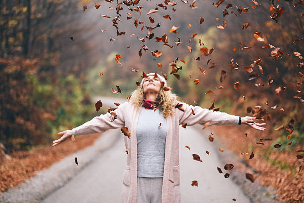 istock Joyful Woman Outdoors Tossing Autumn Leaves On Path In Cozy Fall Outfit 2252877549