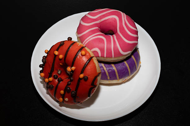 istock Appetizing ring-shaped donuts, decorated with colorful sprinkles and cookie crumbs, on a black background, create. Donuts 2252879518