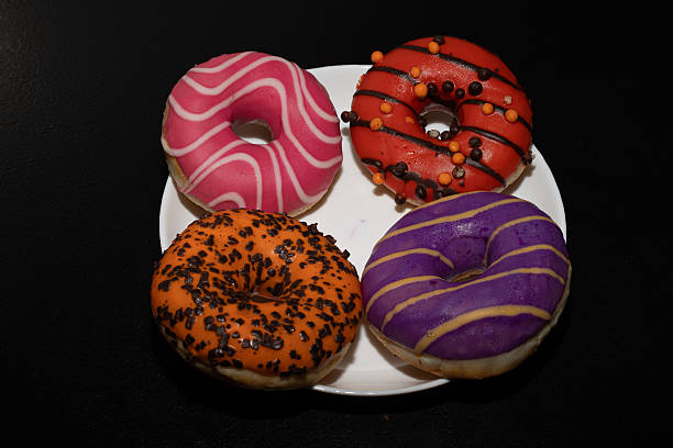 istock Appetizing ring-shaped donuts, decorated with colorful sprinkles and cookie crumbs, on a black background, create. Donuts 2252879581