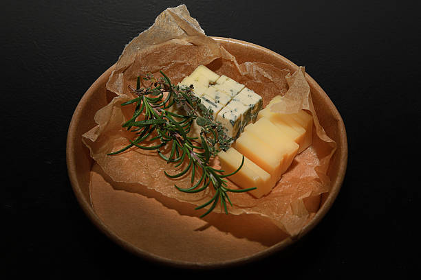 An assortment of fresh cheese blocks with herbs showcased at a local market.