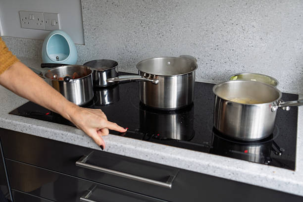 istock Woman's hand activating induction cooktop with multiple pots in contemporary kitchen 2252880118