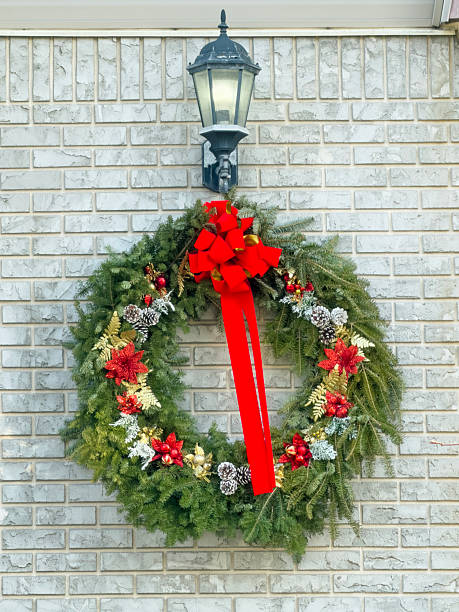 istock Large outdoor Christmas wreath with red bow hanging under lantern on brick wall 2252880407