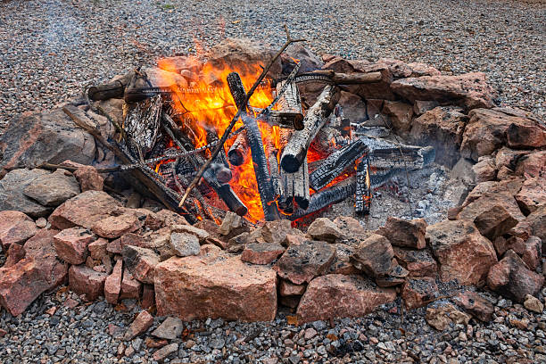 A two-year-old Eurasian boy hands a piece of firewood to his grandfather as he builds a fire in a fire pit located in the back yard of his home in rural Oregon.