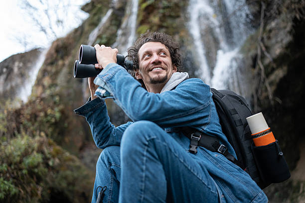 istock Focused Explorer With Binoculars Near a Waterfall While Backpacking in Nature 2252890891