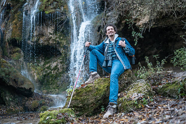 istock Outdoor Explorer With Binoculars By Waterfall: Hiking Enthusiast On Mossy Rock 2252890920
