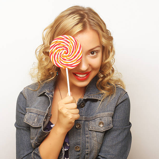 Portrait of a young beautiful blonde woman holding a big candy heart in her hands. Enjoying life.