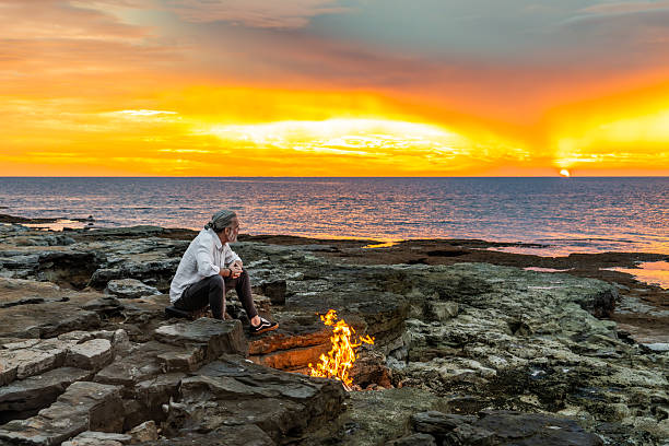 istock Person Sitting by Campfire, Watching Sunset over Ocean 2252899210