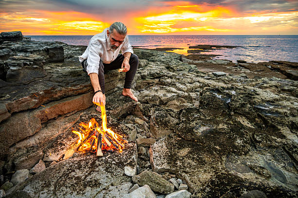 istock Man Meditating by Campfire at Sunset on Rocky Terrain 2252899211