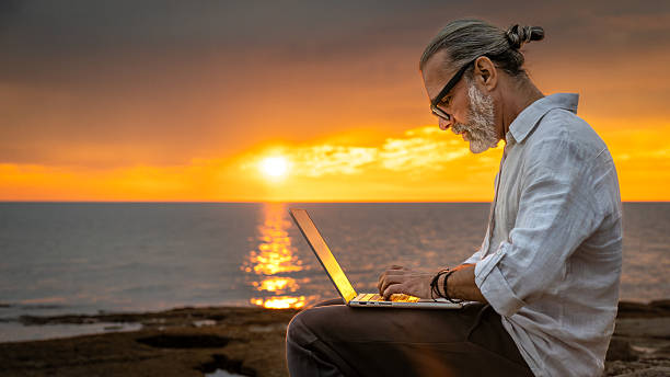 istock Man Typing on Laptop by the Sea at Sunset 2252899226