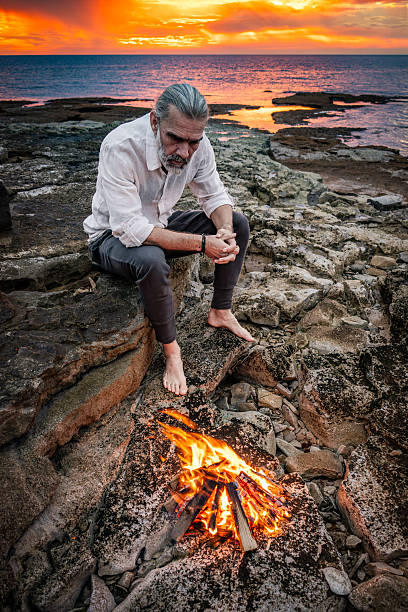 Solitary Man Reflecting beside Campfire at Sunset