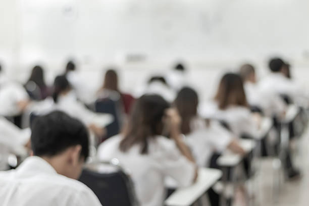 istock Blur school student exam background in university class with blurry view from back of the classroom of young people having stress doing examination admission test in classroom for education 2252900118