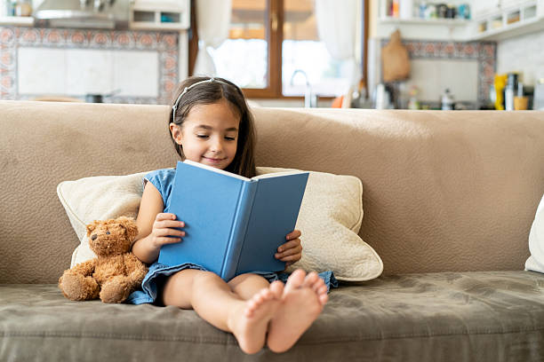 istock Close up of small girl reading on a sofa 2252903151