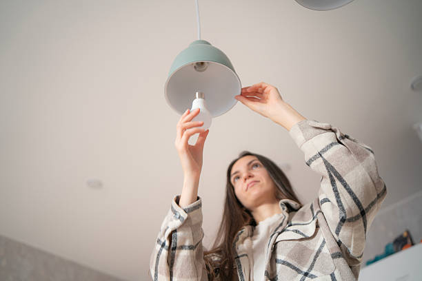 istock A woman carefully replaces a light bulb 2252910012
