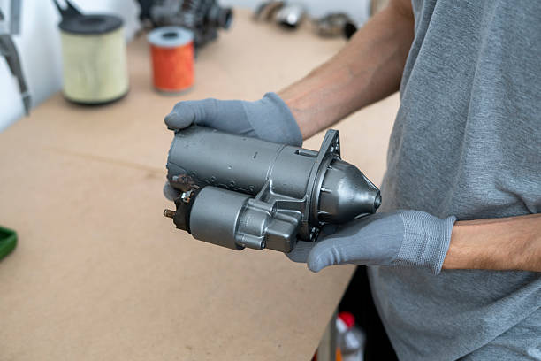 istock Mechanic inspects a car starter component while wearing gloves in a well-equipped garage, focusing on the details crucial for efficient repairs. 2252914717