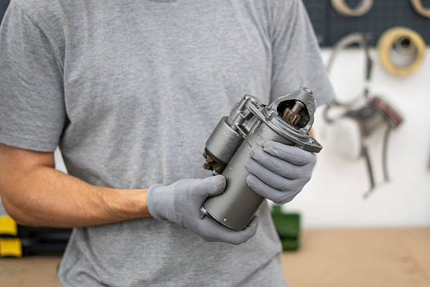 istock Mechanic inspects a car starter component while wearing gloves in a well-equipped garage, focusing on the details crucial for efficient repairs. 2252914721