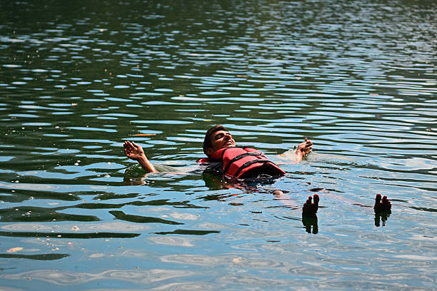 A man floating calmly on a lake while wearing a life jacket, enjoying a peaceful moment on the water. It represents relaxation, safety, adventure, and connection with nature. The scene captures an outdoor water activity during a travel experience, symbolizing freedom, mindfulness, stress relief, and enjoyment of natural surroundings. Ideal for concepts related to water adventure, outdoor recreation, travel lifestyle, safety awareness, wellness, leisure, vacation.