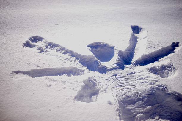 Aerial view of a boy lying in the snow making a snow angel