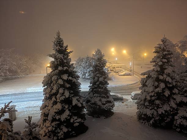 Brno, Czech Republic - January 20, 2023: Winter night in the city with snow-covered cars, sidewalks and roads. Snow disaster in a housing estate in Eastern Europe.