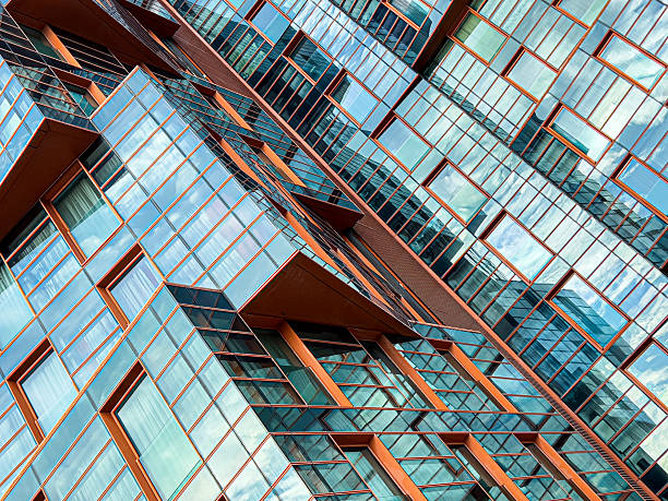 Contemporary glass facade of a skyscraper reflecting the clear blue sky and angular architecture