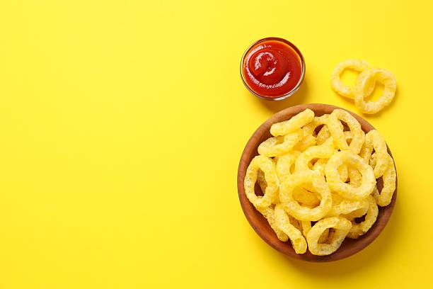 istock Corn ring crisps with ketchup on yellow background, top view 2252927098