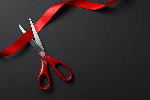 istock Beautiful red ribbon and scissors on black background, flat lay with space for text. Ceremonial tape cutting 2252928826