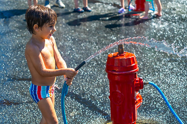 A boy has fun spraying a garden hose in his backyard.