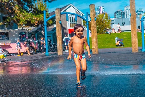 Happy child running through jets of water in a splash park on a summer day in vancouver, british columbia, canada, enjoying the refreshing spray and the playful atmosphere