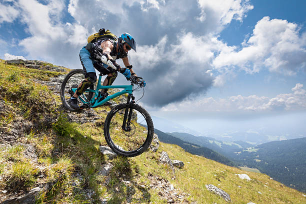 An experienced and well equipped adult male mountain biker on his steep downhill ride over a rocky passage on a narrow footpath above the tree line at scenic Carinthian mountains of Austria.Canon EOS 5D IV, 1/800, f/9, 16 mm.