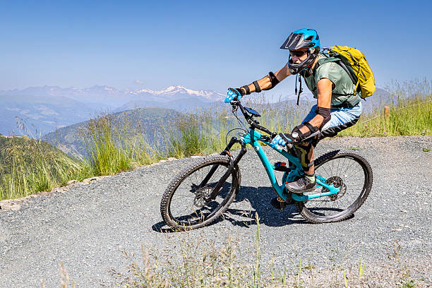 An experienced and well equipped male mountain biker is riding down a curve of the marvellous flow trail of Bad Kleinkirchheim in Austria with scenic view to snowcapped mountains.Canon EOS 5D IV, 1/1000, f/11, 25 mm.
