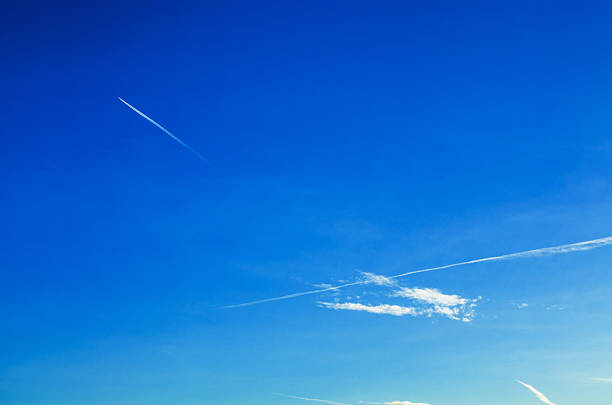 Blue sky with airplane contrail and small cloud symbolizing passing time