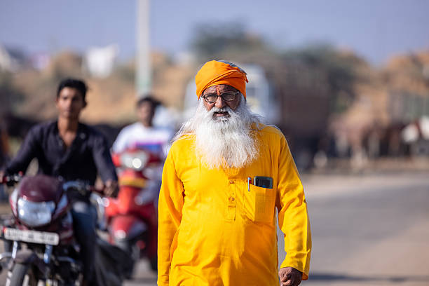 Pushkar, Rajasthan, India - November 2024: Portrait of a rajasthani male in traditional white clothes with colourful turban at desert fair ground during the pushkar camel fair to trade camels.