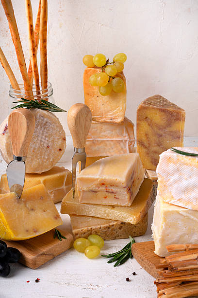 Assorted cheeses, fig jam, honey, grape, grissini and knives on light background