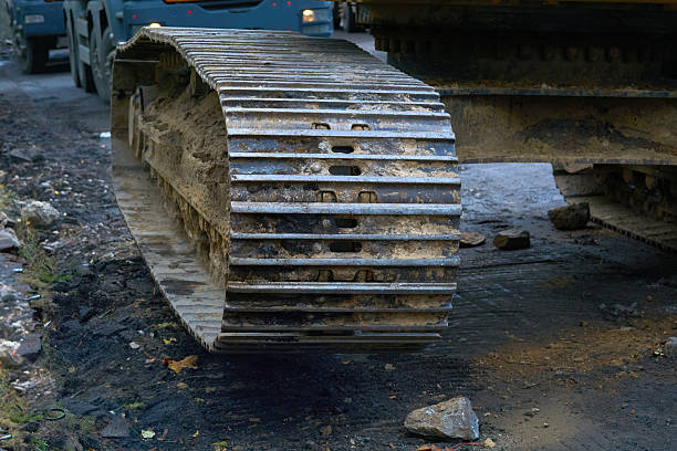 A heavy yellow loader, likely used in construction or mining, stands outdoors. The machine is visibly dirty, with mud splattered on its exterior and tires, and it looks like an industrial landscape