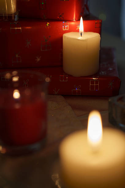 istock warm candlelight illuminates festive scene with stacked red gift boxes adorned with shimmering patterns, creating a cozy and inviting holiday ambiance in soft-focus setting, reflective, holidays 2252937764