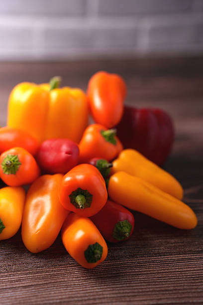 istock vibrant array of red, orange, and yellow peppers artfully arranged on a rustic wooden surface with a soft out-of-focus brick wall background creating a warm, inviting kitchen atmosphere, focus 2252938213