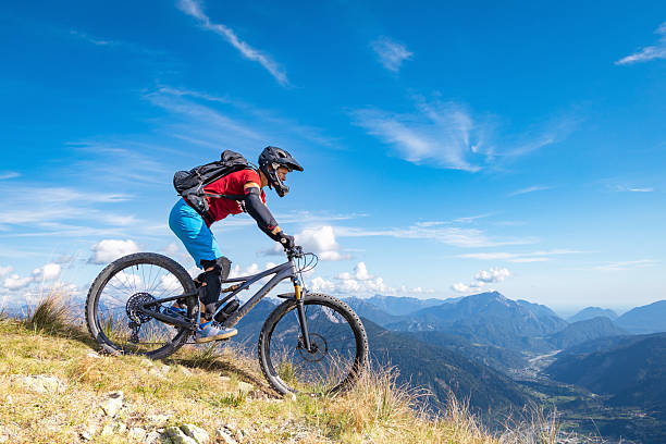 Young man riding his mountain bike in nature in front of majestic mountains