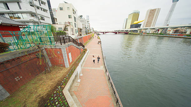 Two multi-racial male and female athlete runners are running and springting in the city in Tokyo.