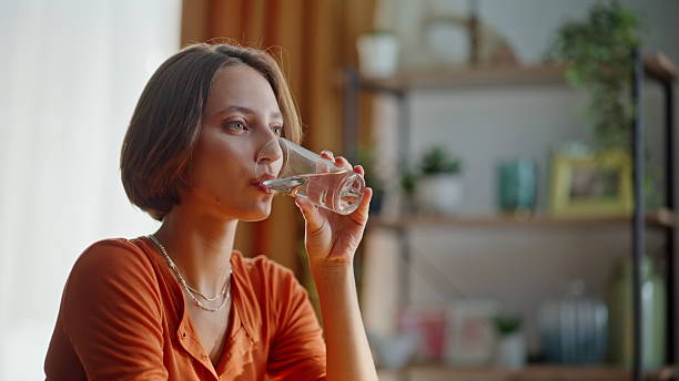 istock Brunette drinking fresh water sitting alone at modern kitchen interior closeup. 2252944668