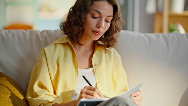 istock Home woman writing notebook sitting modern couch in light apartment closeup. 2252945286