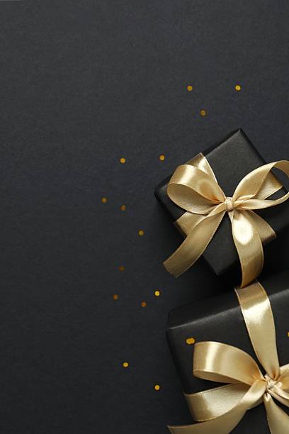 istock Beautiful gift boxes tied with golden bows on black background 2252945342