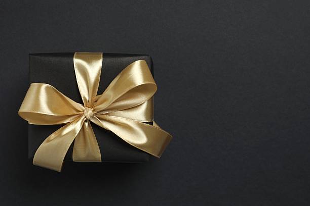 istock Beautiful gift box tied with golden bow on black background 2252945345