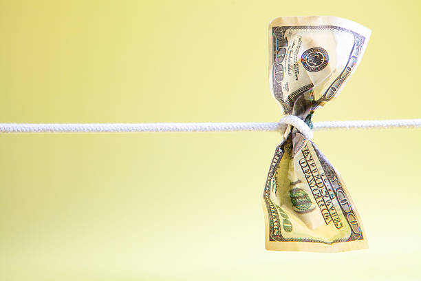 istock Dollars on a clothesline on a yellow background with copy space 2252945596