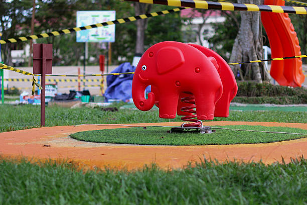 Close-up of a concrete elephant-shaped slide in an outdoor playground, highlighting the textured details and smooth curves of its trunk.