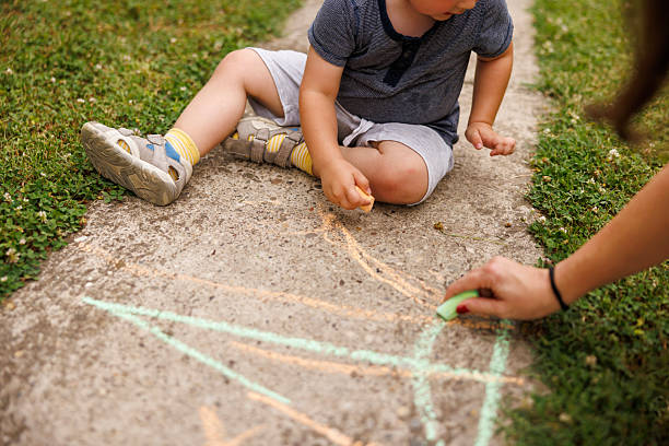 istock Mother and son having fun drawing with chalks on concrete path 2252950898